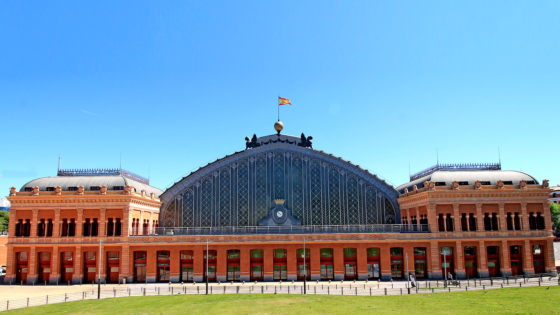 La gare d'Atocha se dresse dans la capitale de l'Espagne, Madrid. Inaugurée en 1851, elle était la première gare de Madrid et a été instaurée par la reine Isabelle II, à l'instar de deux autres gares madrilènes : Delicias et celle du Nord. Quant à la gare d'Atocha, ravagée par un incendie quelques dizaines d'années plus tard, elle a été reconstruite en fer entre 1888 et 1892. Face à l'entrée de la gare, un mémorial a été érigé en hommage aux quelque 200 personnes tuées dans l'attentat du 11 mars 2004.© Luis García, CC by-sa 4.0